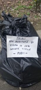 Rifiuti lasciati fuori dai cassonetti, compare un cartello di protesta in piazza Baracca
